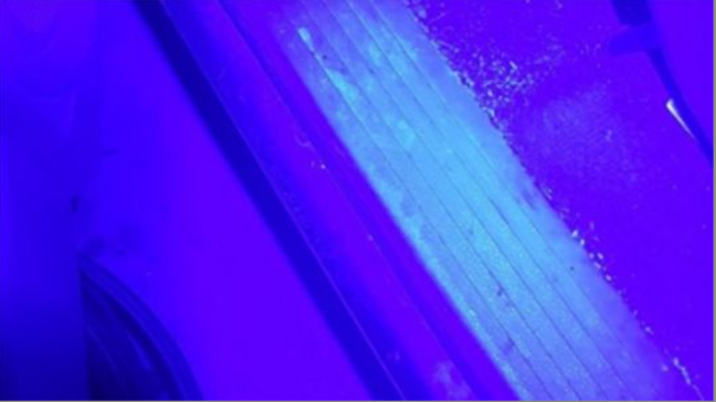 The alleged remains of a blood stain on the floor board of a vehicle are illuminated with Luminol.